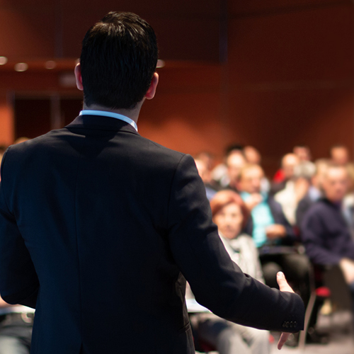 Man conducting training to room of people, with his back to the camera.